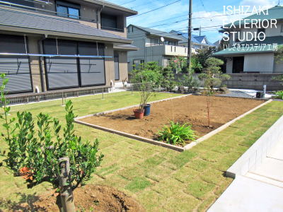 ペット用スペースと花壇、芝生とエリア分けされた施工後の庭